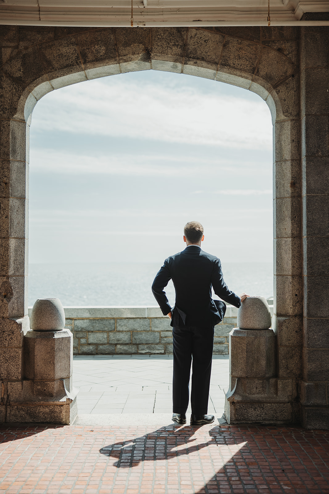 Groom Looks Out at Coastline During Rainy New England Wedding